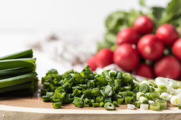 Sliced ​​green onions, red radish in the background