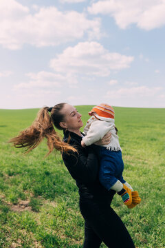 Woman with a baby in her arms standing on a green meadow