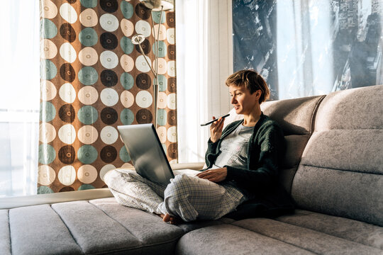 A woman at home communicates with voice messages and uses a laptop