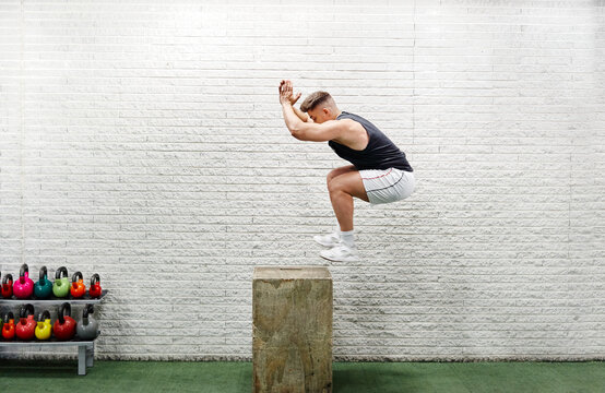 Young Man Jumping Mid Air On Gym Box With Arms Reaching Out
