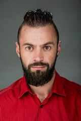 Obraz premium funny guy with a beard in a red shirt close-up shows different emotions. cheerful kind sad surprised satisfied range of emotions