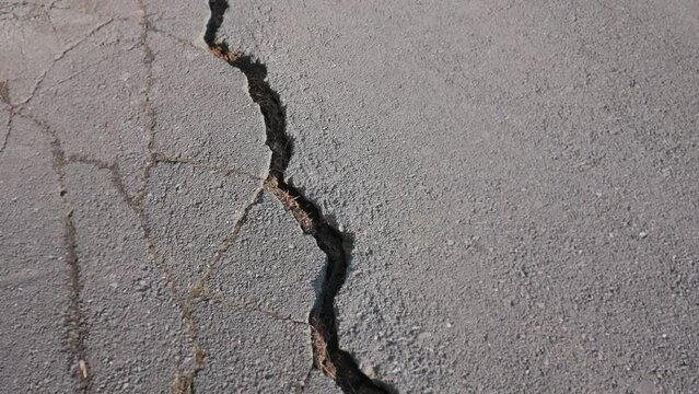 tracking shooting of crack with deep fault on the road, surface rupture on old highway, consequences of man-made or natural disaster.