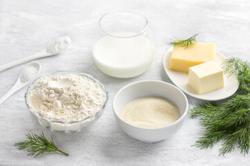 Vegetarian baking ingredients: flour, semolina, cheese, butter, yogurt, dill, salt and baking powder on a light gray background. Cooking delicious homemade food