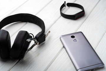 Gadgets on the table. Phone, headphones and fitness tracker on the table
