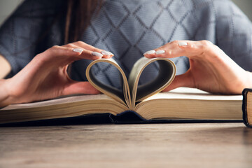 Woman holding a book pages in heart
