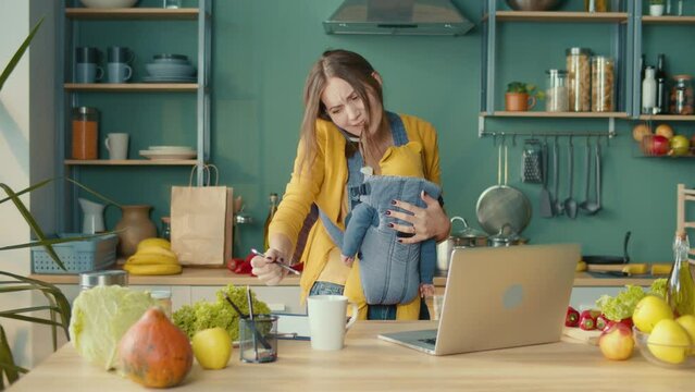 Stressed Mom Soothes The Child on the Hands While Answers the Call and Remote Working at Home. Exhausted Female Working Remotely During an Economic Crisis. Business Woman Rocking Baby on Hands.
