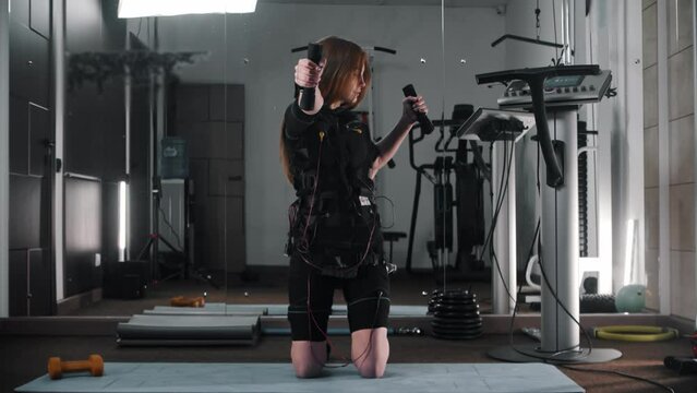 Young woman training in ems suit in the gym