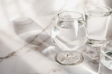 Sunlight through glass of water make light and shadow make a beautiful pattern by refraction of light on white background.