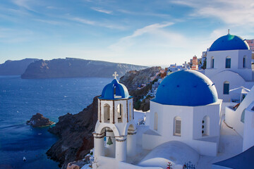 Fototapeta na wymiar Santorini famous view. Blue domed churches on the Oia cliff with Aegean sea and Caldera in background.