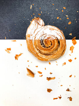 Delicioso cinnamon roll em fotografia art&iacute;stica com fundo preto e branco.