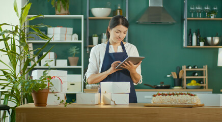 Successful Female Small Business Owner Prepares a Customer Order. Modern Designer Kitchen. Confectionery and Favorite Business. Organization of Work in the Field of Delivery. Startup.