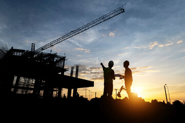Fototapeta na wymiar Engineers and workers inspecting projects at the construction site background. Construction site at sunset in the evening, Asian engineer silhouette