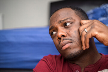 Fototapeta premium Depressed and anxious African American or black man sitting at home
