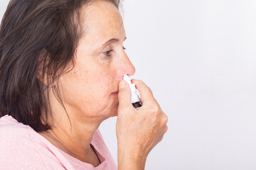 Side view of a woman using nasal spray - isolated.
