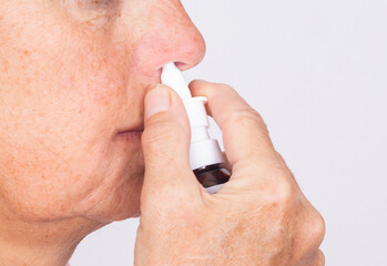 Close up of woman hands using nasal spray - isolated.