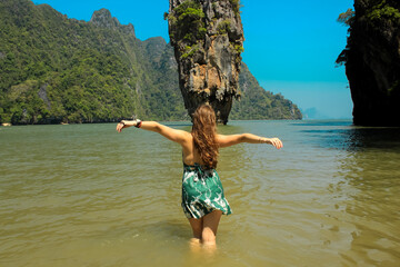 A girl with long copper hair with her back next to James Bond's island Koh Tapu in Phang Nga bay,...