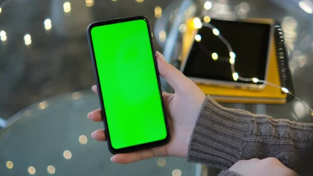 Mall.Use green screen for copy space closeup. Chroma key mock-up on smartphone in hand. Woman holds mobile phone and looking photos or pictures