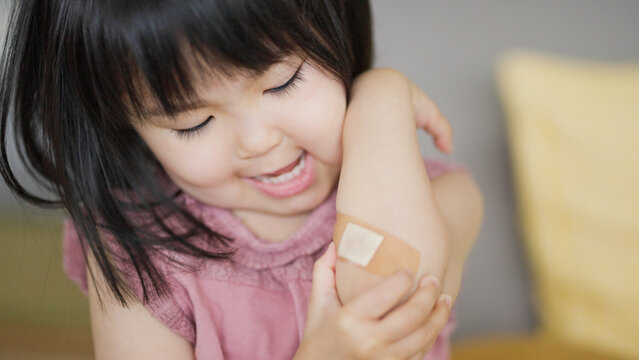 怪我をした腕の絆創膏を気にする4歳の子供（育児・子育て）