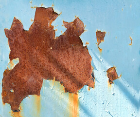 A rust stain on a metal surface painted with blue paint.