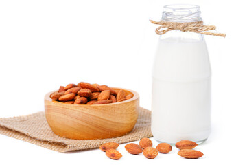 Glass bottle of milk with almond in hemp fabric bag on white background.