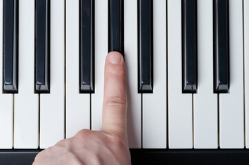 Finger press black key on piano