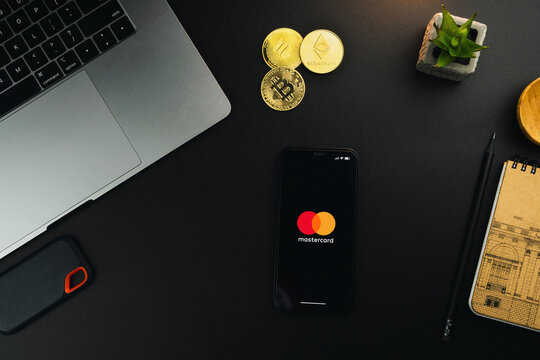 Mastercard payments system app on smartphone screen on black table with a cryptocurrencies coins and computer. Office environment. Rio de Janeiro, RJ, Brazil. May 2022