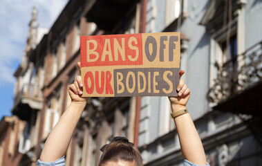 Woman holding sign with slogan Bans Off Our Bodies. Protester with placard supporting abortion rights at protest rally demonstration.