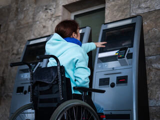 A Caucasian woman in a wheelchair does not reach the self-service checkout at the railway station....