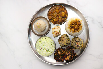 Indian vegetarian lunch or dinner Thali includes beans sabzi, dal rice, Alu Vadi, dhokla, veg...