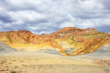 Multi-colored mountain made of yellow and orange mineralized soil and rock. Natural painted stone.