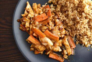 Chicken stir fry in peking sauce on a black plate.  Traditional Chinese food.  Flat lay top view photo. 