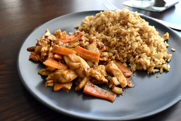 Chicken stir fry in peking sauce on a black plate.  Traditional Chinese food. 