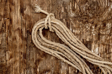 Obraz premium Coil of old rope on a dark wooden background. Worn, dirty rope.