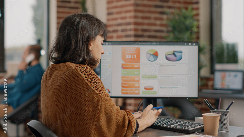 Wall mural business woman working on project planning with rate charts and information, using computer keyboard