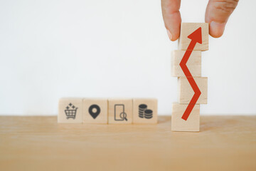 businessman's hand completed increasing arrow sign on wooden cube blocks and blurred business icon...