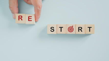 senior's hand holding wooden cube blocks with re start text , dartboard instead of letter a for New...