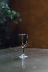black charcoal lemonade cocktail drink in vintage iridescent glass on muted gold brass table	
