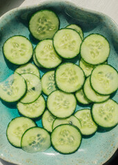 fresh sliced cucumber wheels on teal plate