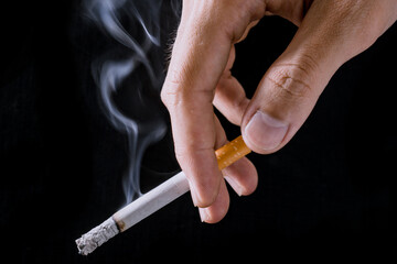 Cigarette.Closeup hand of man holding a cigarette.tobacco cigarette butt on the floor.World no tobacco day.Sign of stop smoking for no smoking day.