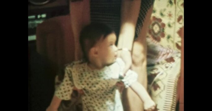 First baby steps with mother help in soviet apartment interior. Mom supports child taking first steps. Mother care. Vintage color film. Cinema lens flare. Family home archive 8mm. Retro 1980s-1990s
