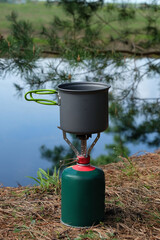 Camping gas burner with a pot on the coast of the river