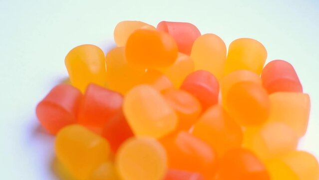 Close-up texture of orange and yellow multivitamin gummies in the form of bears on white background. 