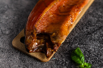 Whole smoked trout on a wooden board on a dark background. Snack