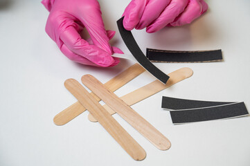 Manicurist in pink gloves uses disposable nail files. 