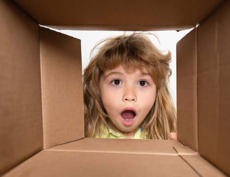 Amazed Adorable Little Boy Peeking Inside Gift Box, Unpacking Present With Funny Astonished Expression, Impatient Child Unboxing Surprise. Parcel Packaging Or Unpacking Concept. Closeup Kids Face.