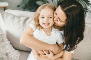 A mother tenderly kisses her four-year-old daughter. 