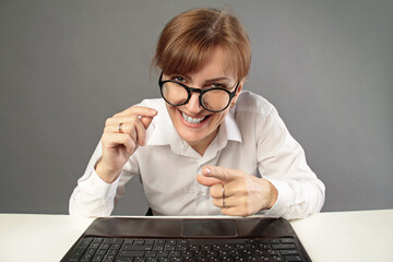 Businesswoman using laptop and looking at the camera isolated on studio grey background