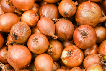 Onions on top of each other for sale at a vegetable store. Texture of the bulbs.