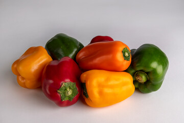 Red, green, yellow and orange bell peppers on a white background