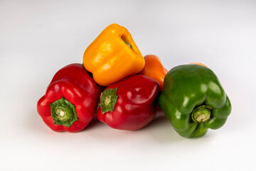 Red, green, yellow and orange bell peppers on a white background